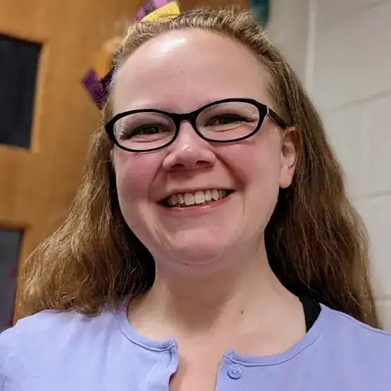 A smiling woman wearing glasses with a purple sweater on named Meryl Butler is looking into the camera.
